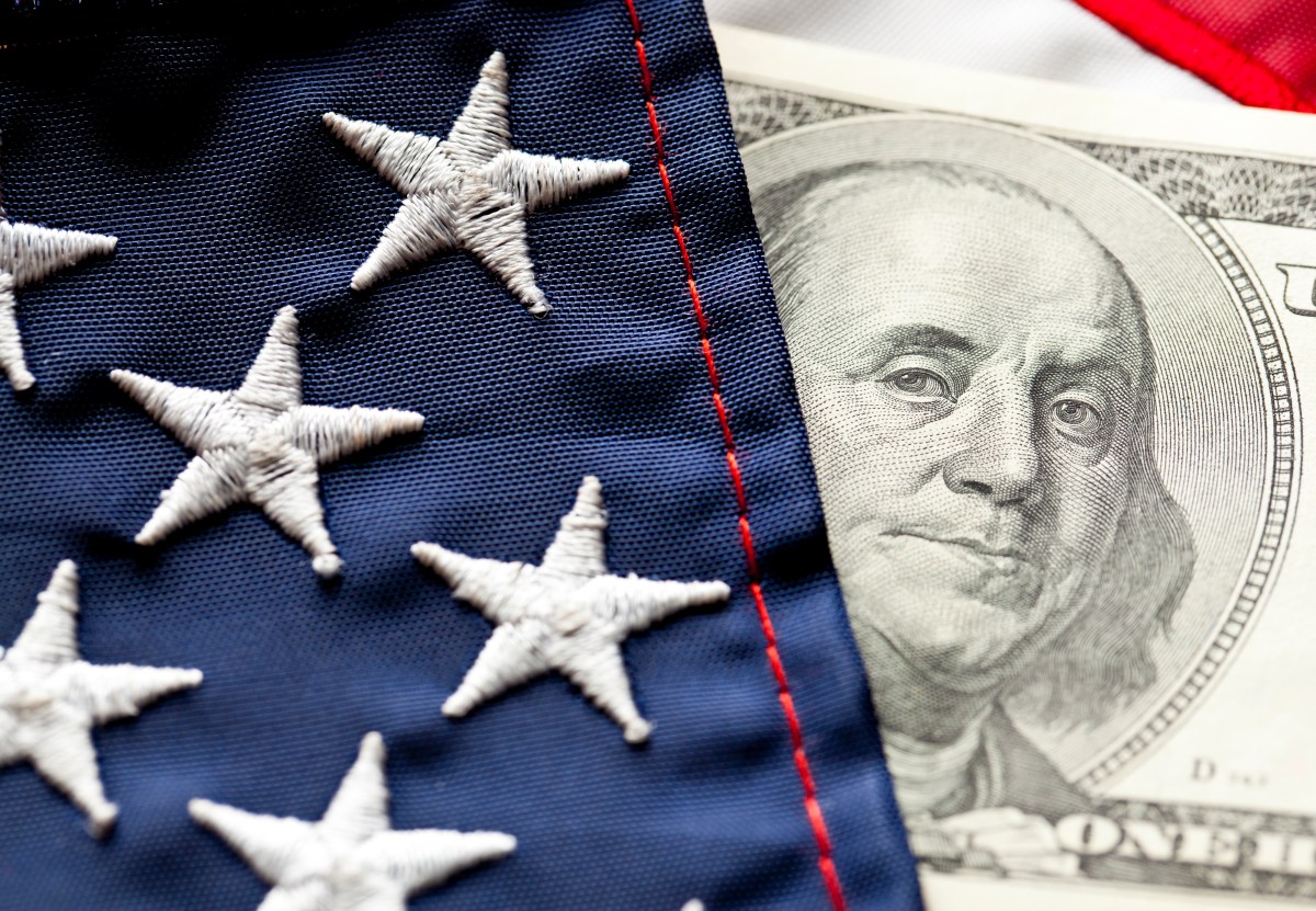 The starred portion of an American flag lies against a $100 bill bearing Ben Franklin's face.