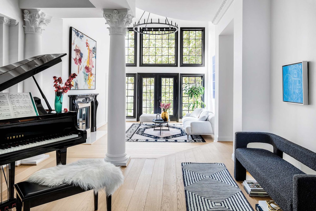 An open room, white walls and black window rims, a piano, a black bench, a pillar, black and white rugs
